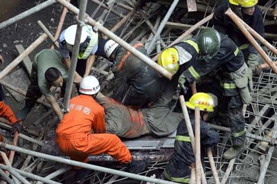 Chinese rescuers pull out a body of a worker crushed after scaffolding of a building under construction collapsed on to some twenty-odd workers, in Zhengzhou, central China's Henan province 06 September 2007.  The accident is the second major workplace accident following the collapse of a 328-metre (1,076-foot) bridge over the Tuo river in Hunan province, killing 41 workers who were removing steel scaffolding erected during its construction.                CHINA OUT GETTY OUT   AFP PHOTO (Photo credit should read STR/AFP/Getty Images)